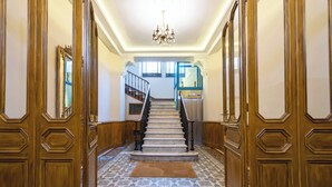 Un vaste hall d’entrée avec un escalier en marbre, des boiseries et des carreaux de sol à motifs.
