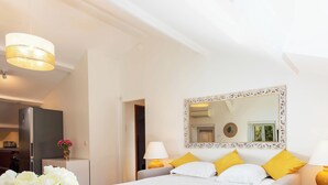 Una camera d'albergo con un letto, lampade sui comodini, uno specchio e vista sulla cucina.