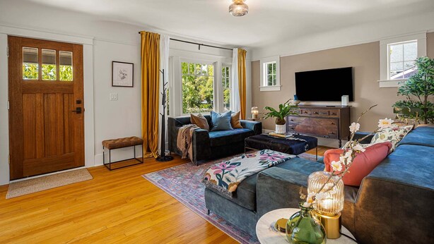 A living room with a sofa, a television, a coffee table, and a plant.