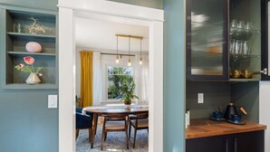 A modern kitchen with a wooden countertop, a dining area with a table and chairs, and a window with curtains.