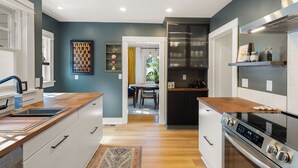 A modern kitchen with a central island, a built-in oven, and a dining area with a view to the outdoors.