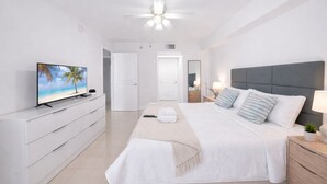 Una habitación de hotel moderna con cama, mesitas de noche, televisor y ventilador de techo.
