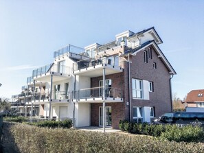 En flervåningsbyggnad med bostäder, balkonger, en fasad av tegel och en klar himmel.