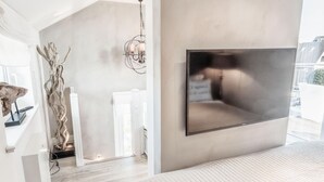 A modern bedroom with a large bed, a mounted TV, and a minimalist decor.