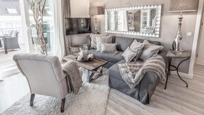 A modern living room with a grey sofa, a coffee table, and a TV mounted on the wall.