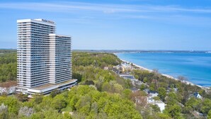 A high-rise hotel with a modern design, located near a beach with a clear view of the ocean.