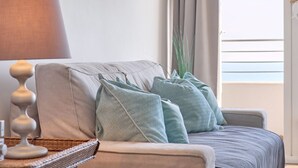 A bedroom with a bed, a lamp, and a view of the sky.