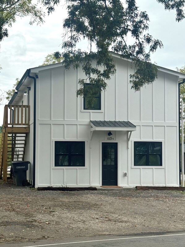 A white building with a black door, two windows, and a small porch. - 601 Serenity Loft in Cookeville  (Cookeville)