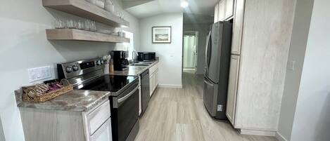 Una cocina moderna con electrodomésticos de acero inoxidable, muebles de madera clara y encimera de mármol.