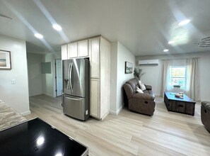 A modern living room with a built-in stainless steel refrigerator, a leather sofa, and a wooden coffee table.