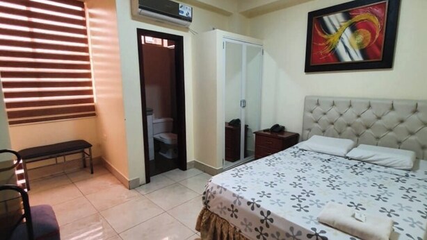 Un dormitorio con cama, un banco, un armario y una puerta que da a un baño.