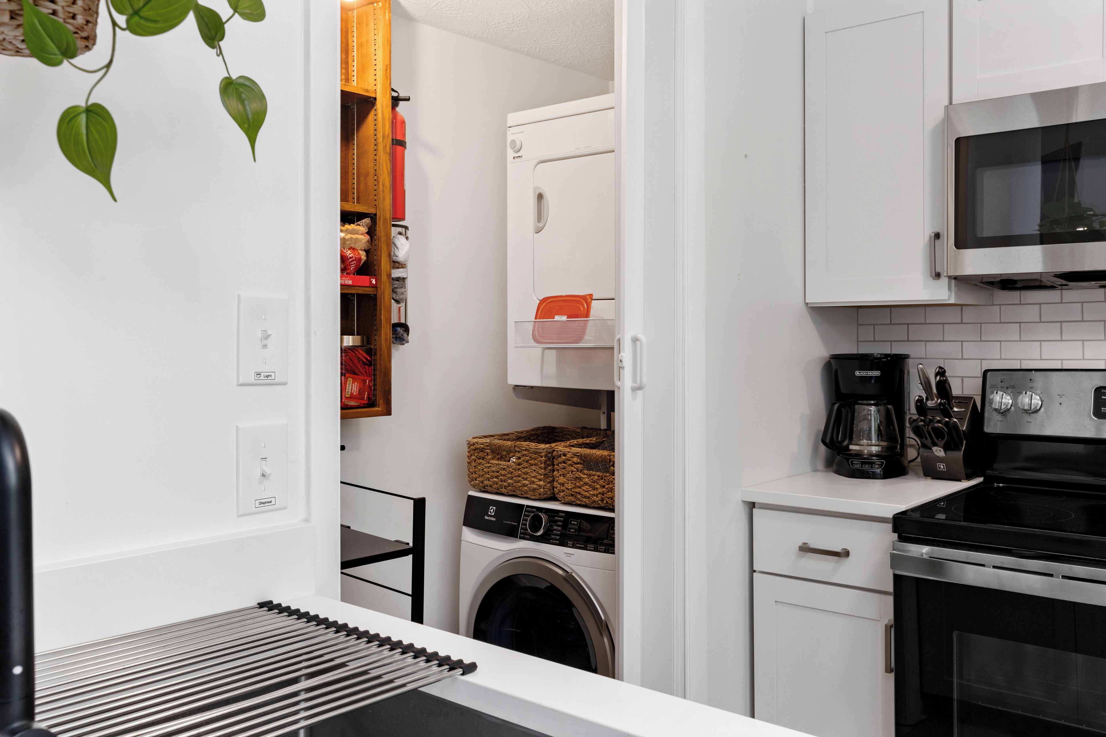 Une cuisine compacte équipée d’un lave-linge, d’un four à micro-ondes et d’une machine à café.