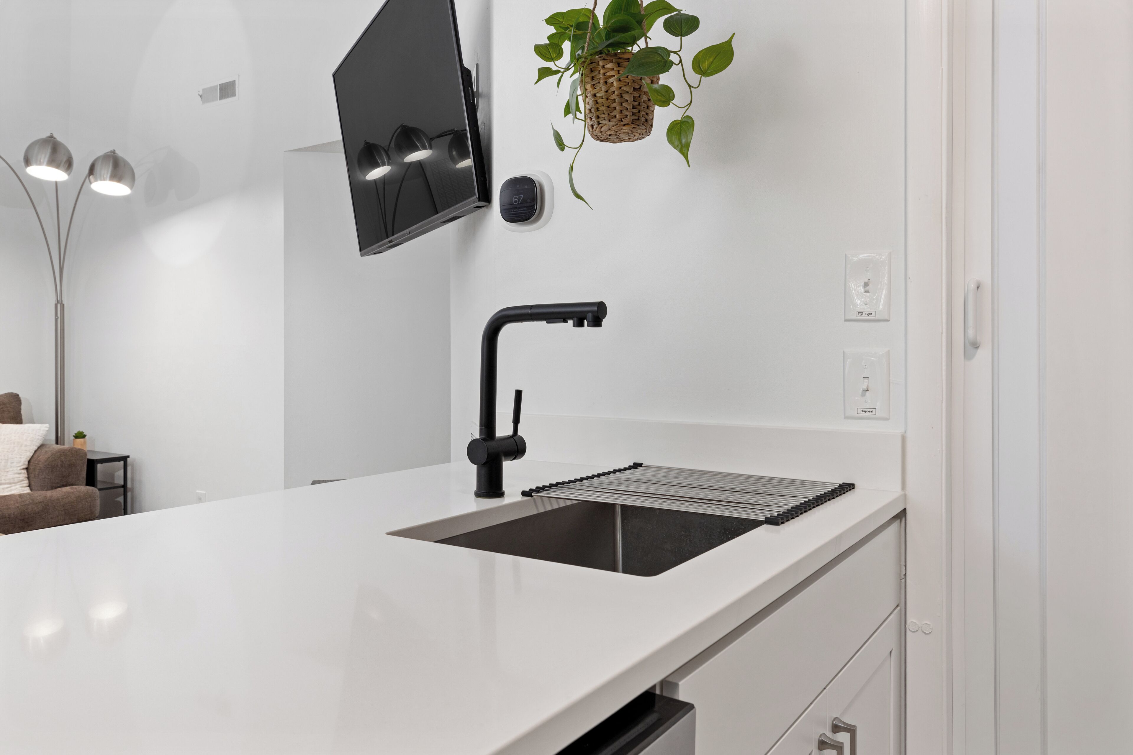 A modern kitchen with a white countertop, black faucet, and a built-in sink.