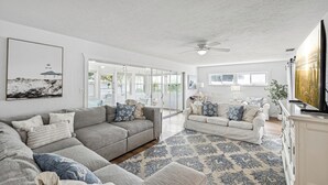 A spacious living room with two sofas, a coffee table, and a large window providing natural light.