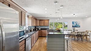A modern kitchen with wooden cabinets, stainless steel appliances, and a central island with bar stools.