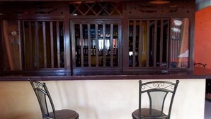Un espace bar avec deux chaises en métal et un comptoir en bois agrémenté d’une grille décorative.