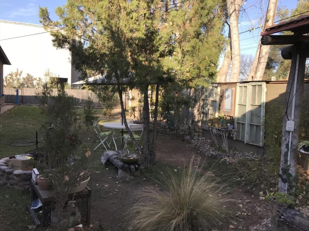 A backyard with a patio, a table, and a covered area.