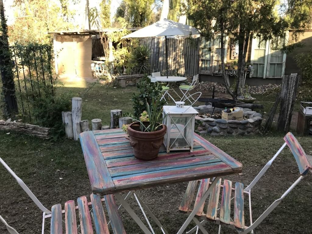 Ein rustikaler Außenbereich mit einem Holztisch, Stühlen, einem Blumentopf und einer Laterne.