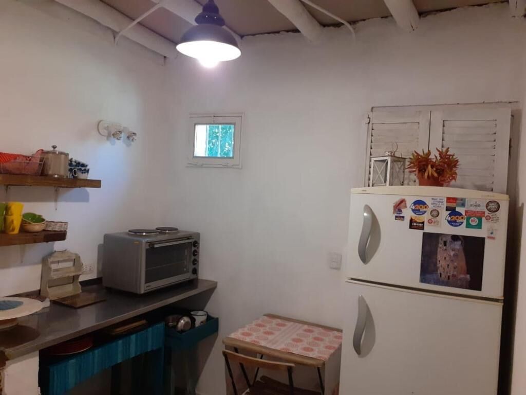 Cocina compacta con refrigerador, microondas y tostadora. Cuenta con un ventanal y una lámpara en el techo.