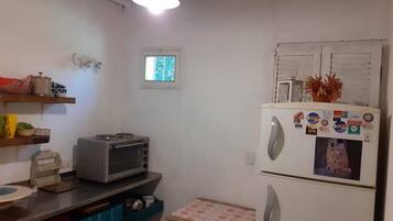 Cocina compacta con refrigerador, microondas y tostadora. Cuenta con un ventanal y una lámpara en el techo.
