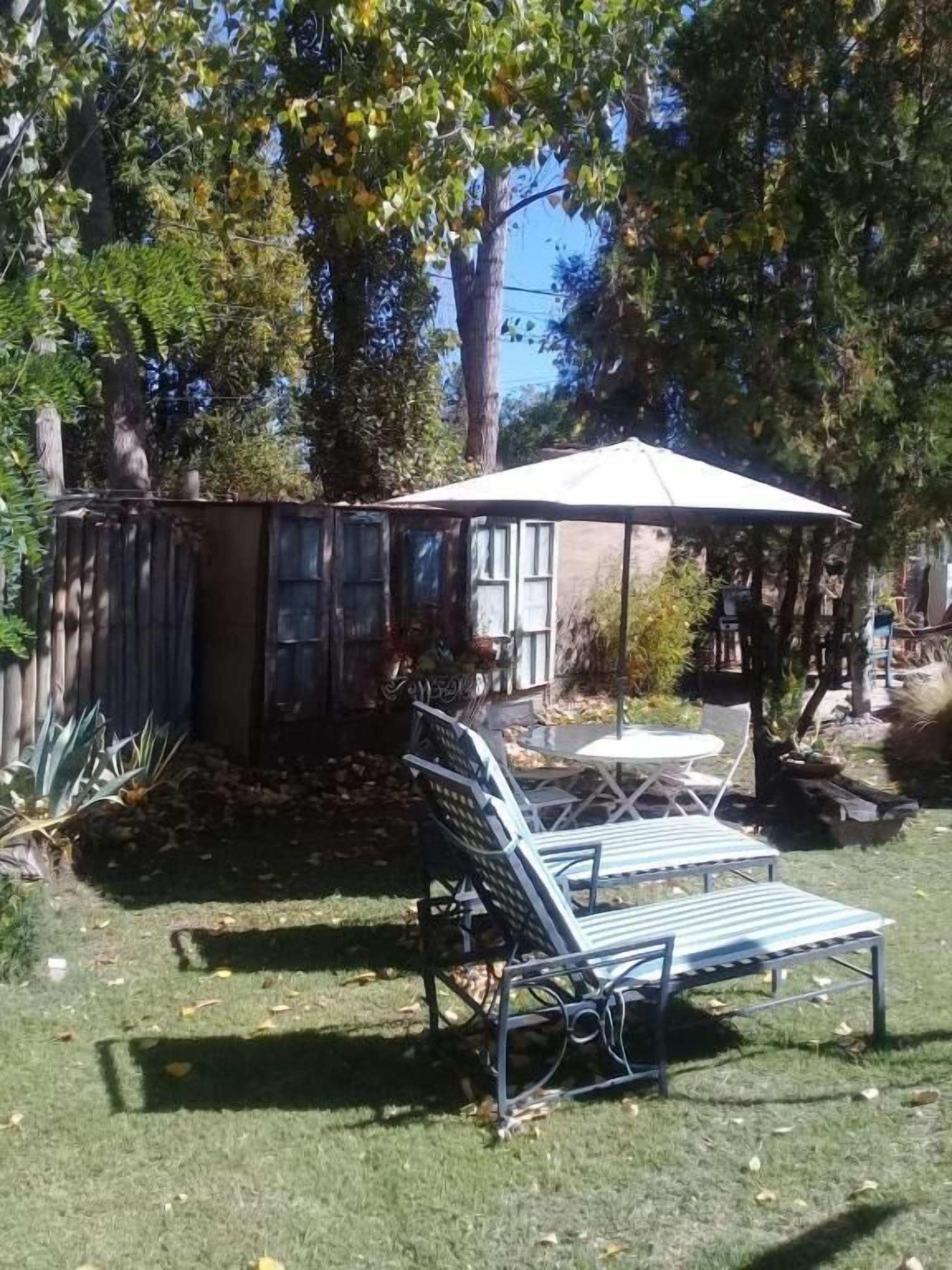 A backyard with a patio table and chairs, surrounded by trees and a shed.