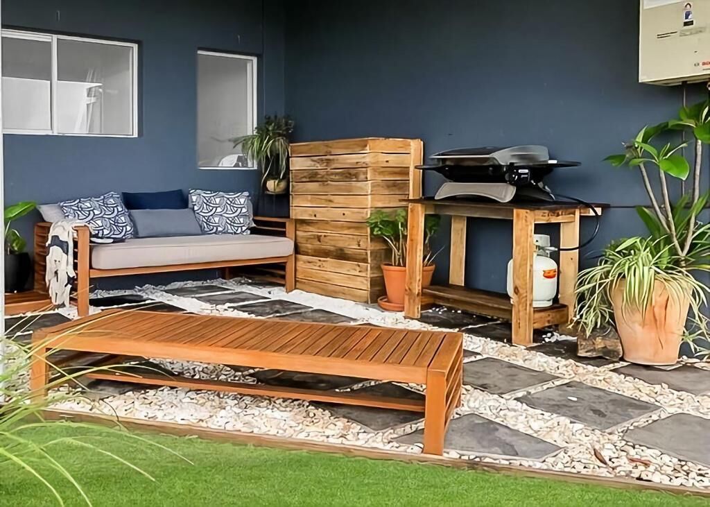 Un espace extérieur accueillant avec un banc en bois, un canapé et une petite table équipée d’un barbecue.
