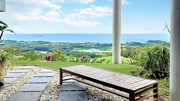 A covered outdoor seating area with a bench, surrounded by greenery and a view of the ocean and landscape. - ON TOP OF THE WORLD Garden Studio
Panoramic Ocean Views, Close to Town & Beaches (Korora)