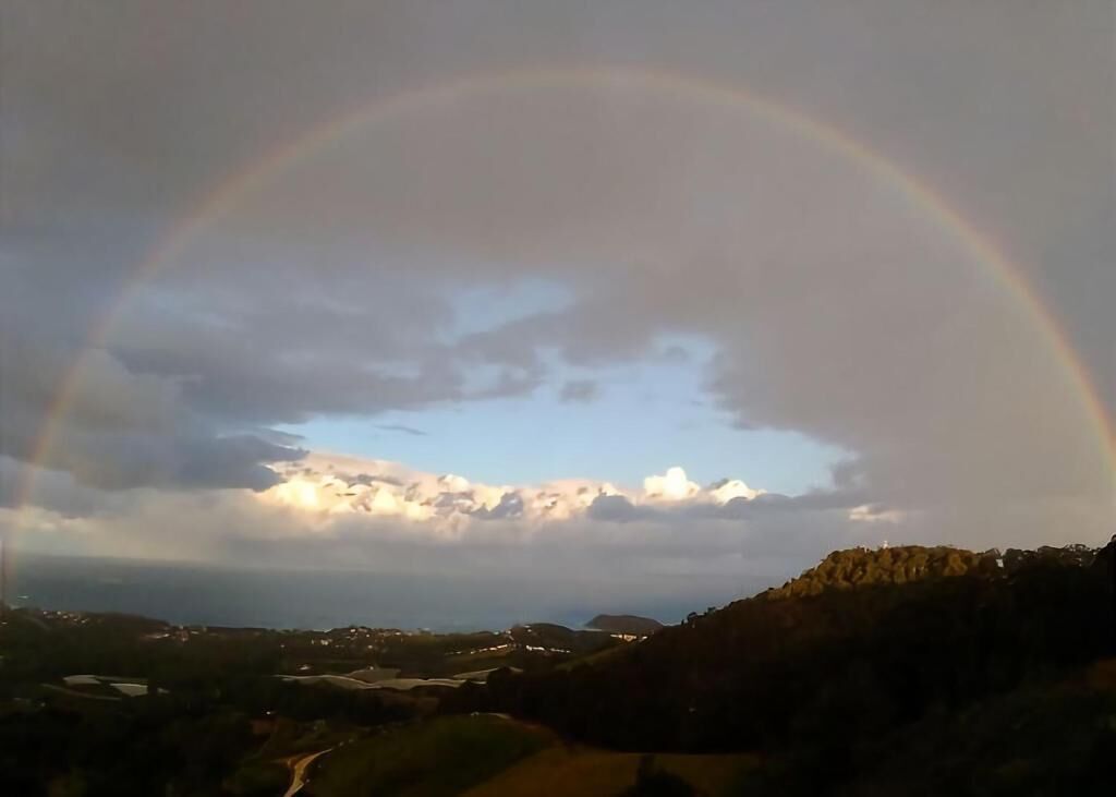 Un paisaje con un arcoíris que se extiende sobre un cielo nublado.