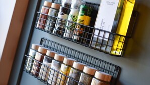Dos especieros metálicos con diversas especias y botellas, incluyendo una botella de aceite de oliva extra virgen.