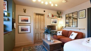 Una habitación acogedora con puerta de madera, una cama, un sofá y una pequeña mesa con una planta.