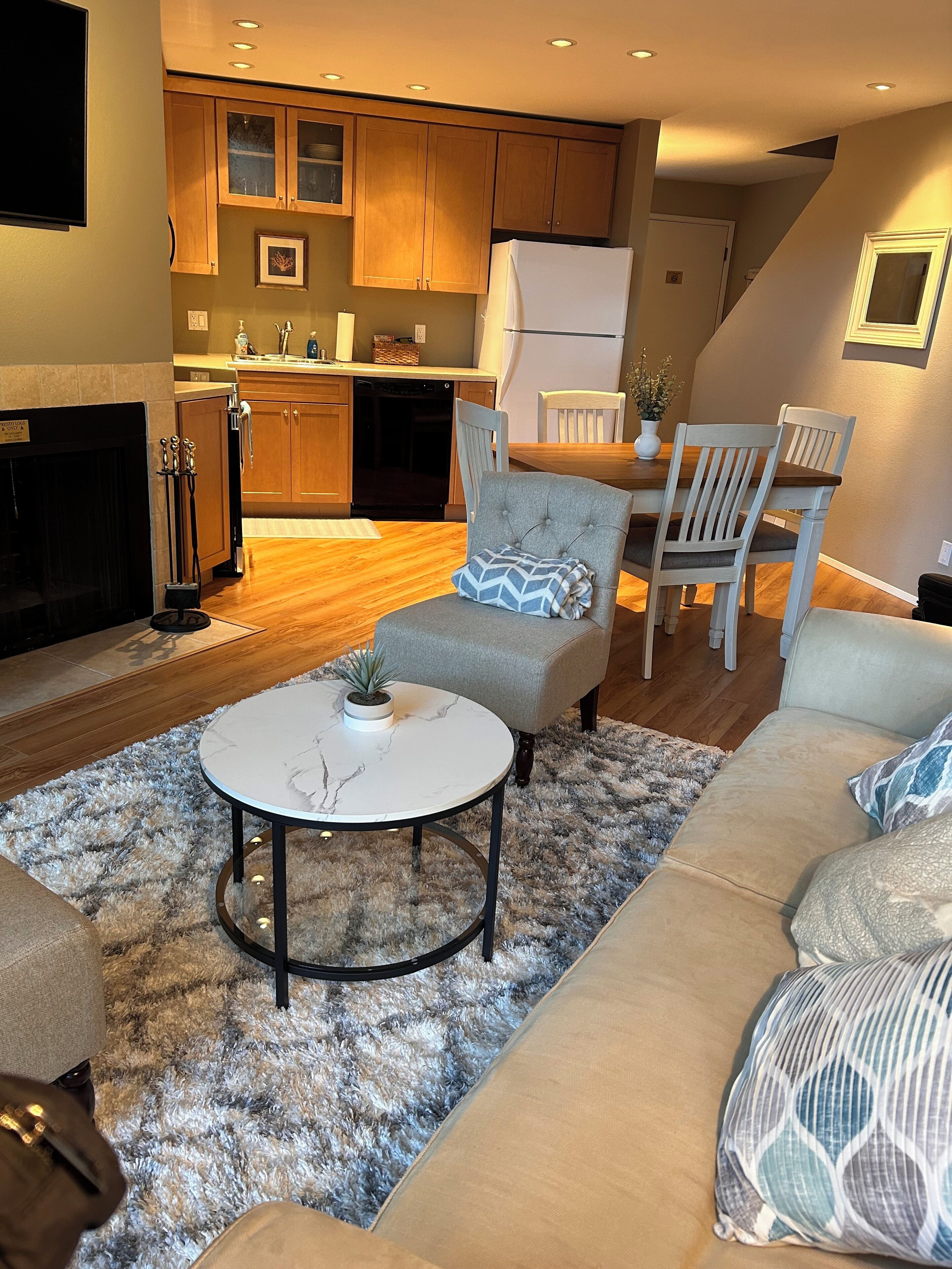 A modern living room with a sofa, a round coffee table, and a fireplace.