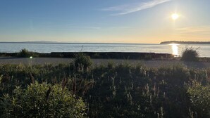 A coastal view with a clear sky, a calm sea, and a distant shoreline.
