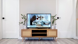 A modern living room with a flat-screen TV on a wooden TV stand, a sofa, and a chair.