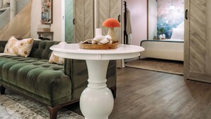 A modern living room with a green sofa, a white round table with a decorative item, and a staircase leading to another room. - Magical Dome Perfect for Families & Groups-Hot Tub-Kid Friendly-Firepit -Private (Nelsonville)