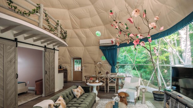 A spacious tent with a large living area, including a sofa, coffee table, and a dining table. - Magical Dome Perfect for Families & Groups-Hot Tub-Kid Friendly-Firepit -Private (Nelsonville)