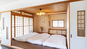 A traditional Japanese room with tatami flooring, sliding doors, and a low ceiling with a hanging light fixture. - Spacious 3-bedroom family-friendly parkside apartment w/WiFi in charming Sapporo (Sapporo)