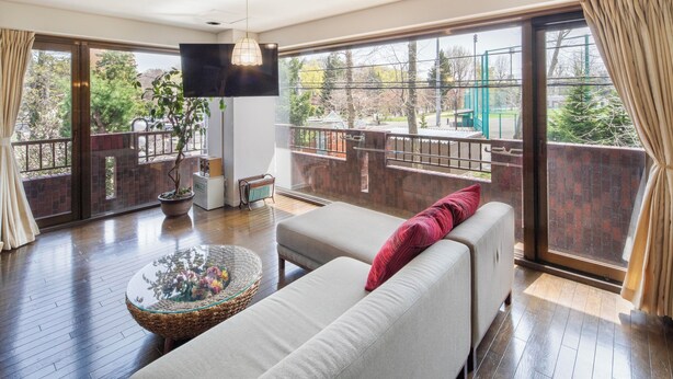 A spacious balcony with a sofa, a glass coffee table, and a TV. - Spacious 3-bedroom family-friendly parkside apartment w/WiFi in charming Sapporo (Sapporo)