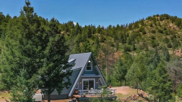 Ein Haus mit einem steilen Dach, umgeben von dichtem Wald.