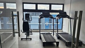 Een sportschool met loopbanden, een hometrainer en een roeiapparaat.