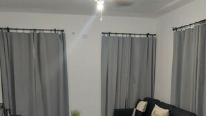 Een moderne woonkamer met een zwarte leren bank, een glazen salontafel en een kleine bijzettafel.