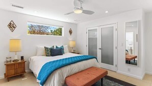 A bedroom with a bed, bedside lamps, a ceiling fan, a window, a sliding door, and a bench. - High Style Bohemian Zen Retreat, Saltwater Pool (Cathedral City)