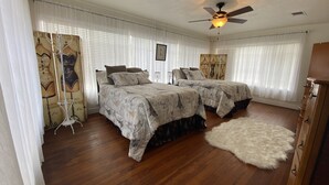 Ein Schlafzimmer mit zwei Betten, einem Deckenventilator und Holzboden.