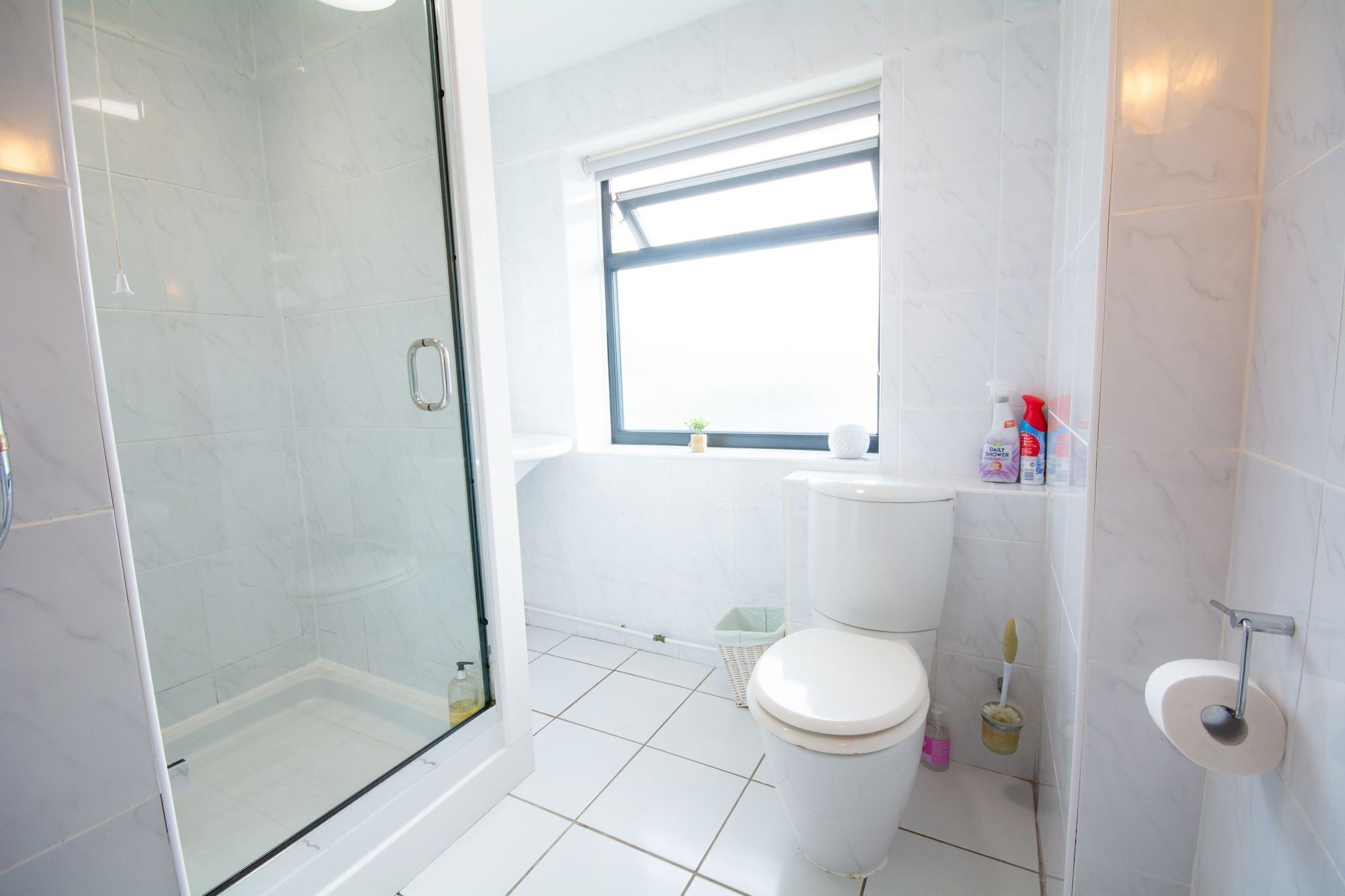 Ein modernes Badezimmer mit Duschkabine aus Glas, Toilette und Waschbecken.