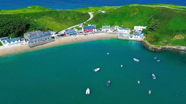 An aerial view of a coastal area with a beach, several buildings, and boats in the water. - 113 Cae Du, Abersoch (Abersoch)