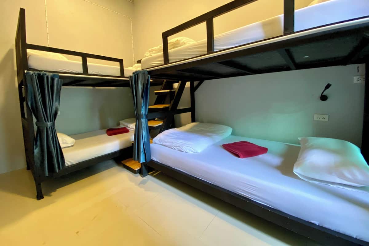 A bunk bed room with a curtain, a small step ladder, and a wall socket.