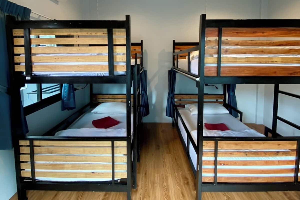 A room with bunk beds, wooden flooring, and an air conditioning unit.