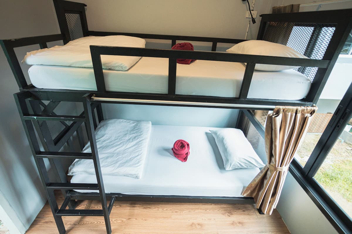 A bunk bed with white bedding and a red towel on the lower bunk.
