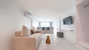 Ein modernes Wohnzimmer mit einer Couch, einem Couchtisch und einem an der Wand befestigten Fernseher.