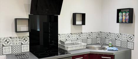 A modern kitchen with a black range hood, stainless steel appliances, and a patterned backsplash.