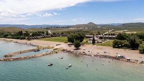 Zona costera con playa, barcos y un conjunto de edificios.